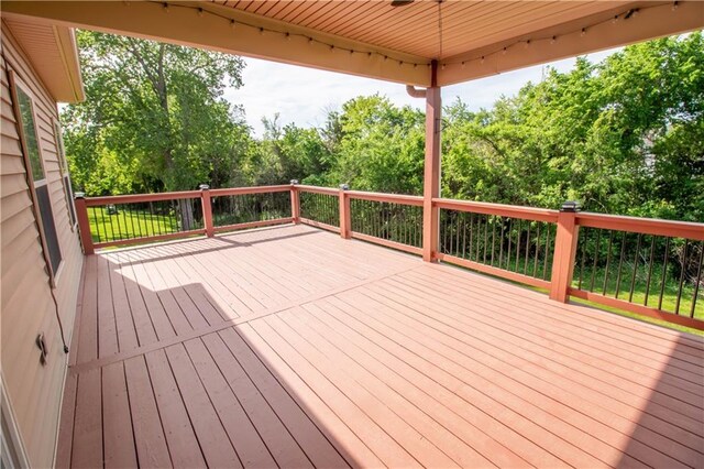 wooden deck with ceiling fan and view of scattered trees