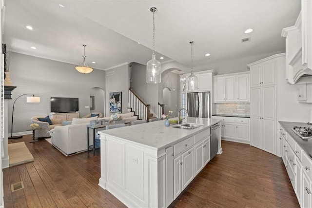 9874 Belmont Dr, Lenexa, KS 66227 - kitchen featuring arched walkways, appliances with stainless steel finishes, a sink, dark wood finished floors, and white cabinetry