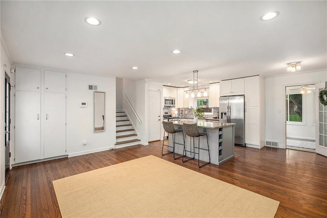 7620 Windsor St, Prairie Village, KS 66208 - kitchen with a kitchen breakfast bar, a center island, dark wood-type flooring, white cabinets, and appliances with stainless steel finishes