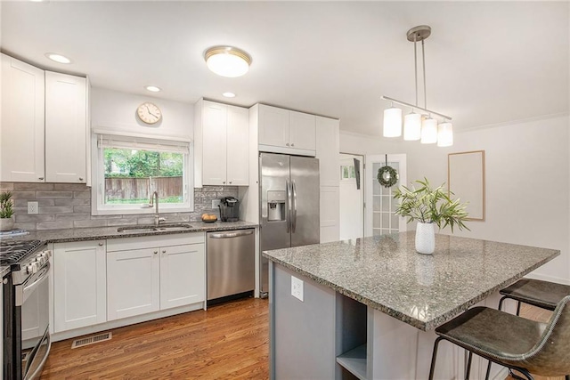 7620 Windsor St, Prairie Village, KS 66208 - kitchen with appliances with stainless steel finishes, a breakfast bar, a sink, light wood-type flooring, and visible vents
