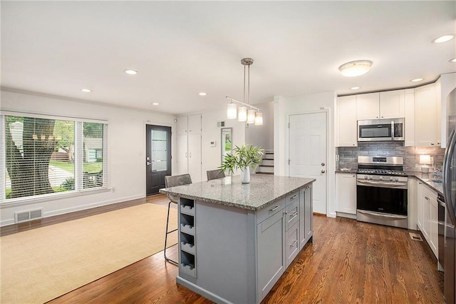 7620 Windsor St, Prairie Village, KS 66208 - kitchen featuring light stone countertops, stainless steel appliances, dark wood-type flooring, backsplash, and visible vents