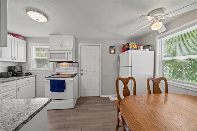 1340 E 85th St, Kansas City, MO 64131 - kitchen featuring white appliances, white cabinetry, wood finished floors, and light countertops