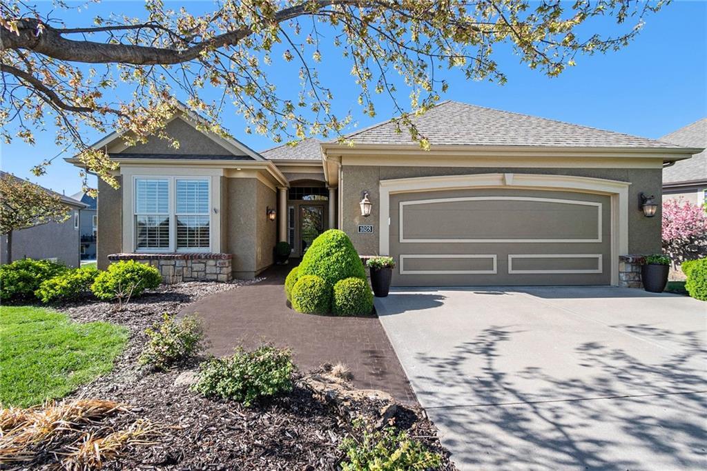 ranch-style home featuring roof with shingles, driveway, stucco siding, and an attached garage