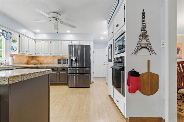 16524 Horton St, Stilwell, KS 66085 - kitchen featuring appliances with stainless steel finishes, light wood finished floors, a ceiling fan, and decorative backsplash
