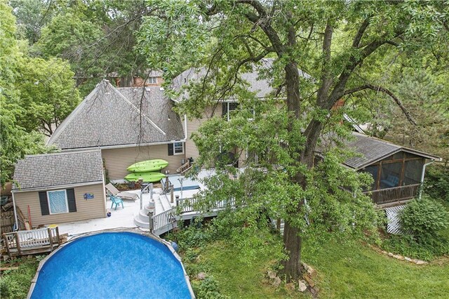 16524 Horton St, Stilwell, KS 66085 - back of house with a wooden deck, a sunroom, roof with shingles, an outdoor pool, and a patio