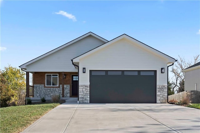 view of front facade featuring driveway, fence, stone siding, and a garage