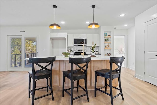 807 N Walnut Ln, Lone Jack, MO 64070 - kitchen featuring appliances with stainless steel finishes, light countertops, light wood-style flooring, white cabinetry, and recessed lighting