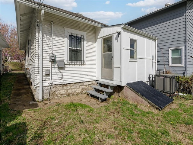 exterior space with central AC unit, a lawn, and entry steps