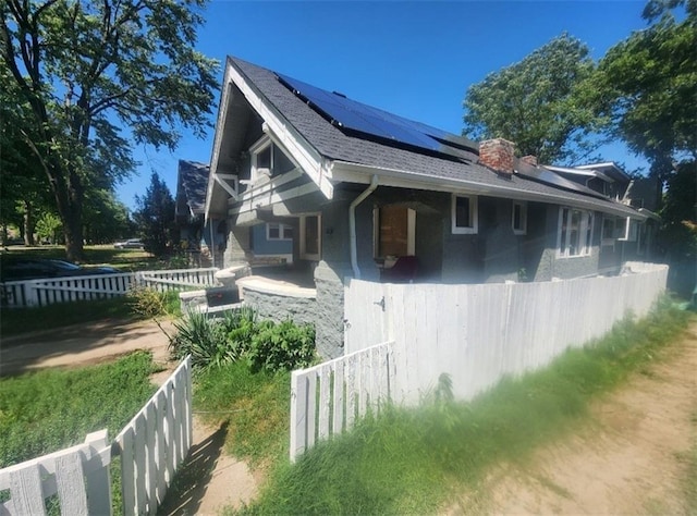 4015 Benton Blvd, Kansas City, MO 64130 - view of property exterior with roof mounted solar panels, a chimney, and roof with shingles