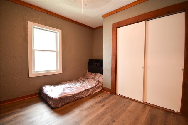 4015 Benton Blvd, Kansas City, MO 64130 - bedroom with a textured wall, wood finished floors, a textured ceiling, and a closet