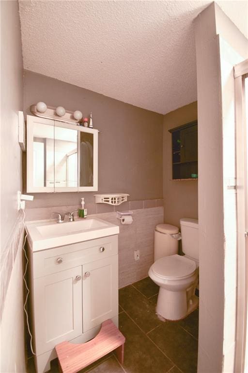 4015 Benton Blvd, Kansas City, MO 64130 - bathroom featuring vanity, tile patterned floors, tile walls, a textured ceiling, and wainscoting