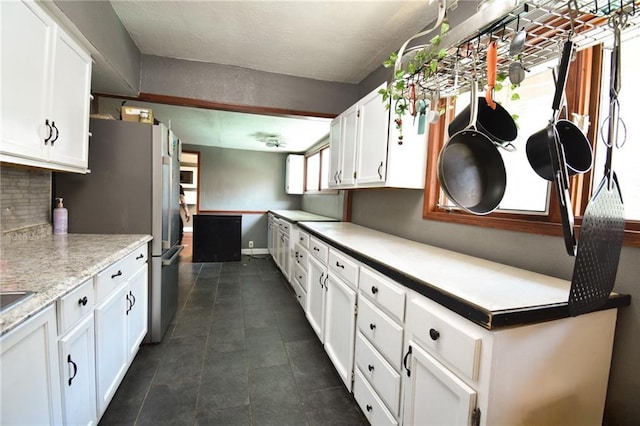 4015 Benton Blvd, Kansas City, MO 64130 - kitchen with freestanding refrigerator, white cabinetry, light countertops, tasteful backsplash, and white microwave