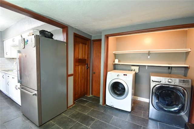 4015 Benton Blvd, Kansas City, MO 64130 - laundry area featuring washer and dryer, a textured ceiling, and dark tile patterned floors