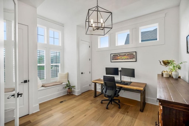 office space featuring plenty of natural light, light wood-style flooring, baseboards, and a notable chandelier