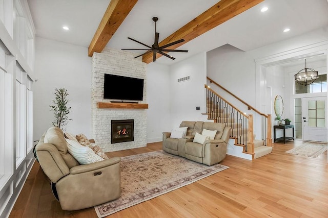 living room with visible vents, ceiling fan with notable chandelier, wood finished floors, and a fireplace