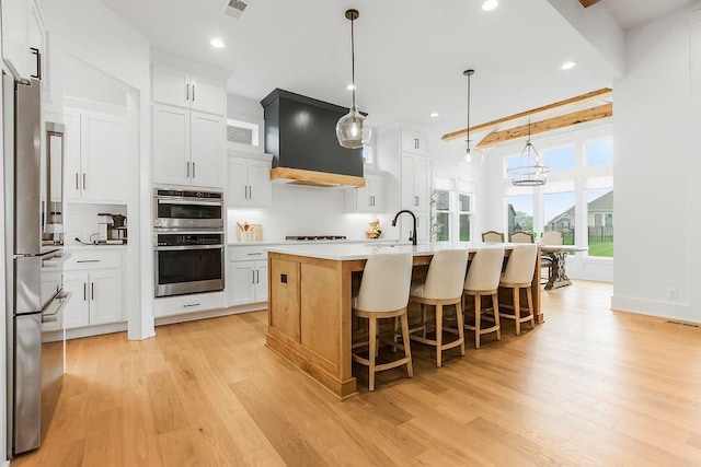 kitchen with decorative backsplash, light wood finished floors, appliances with stainless steel finishes, and light countertops