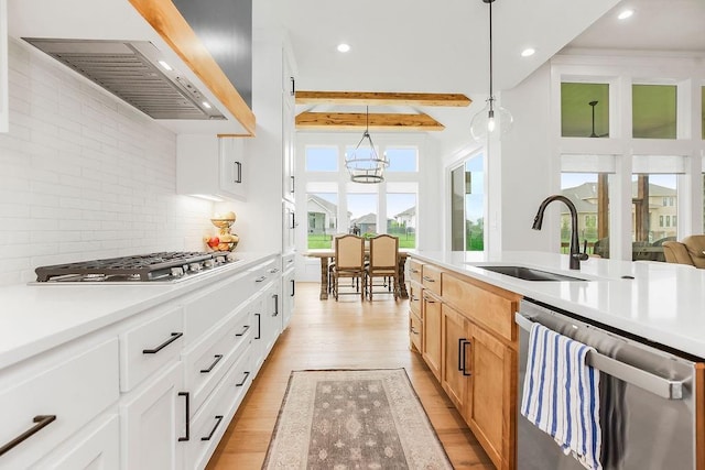 kitchen featuring appliances with stainless steel finishes, a sink, custom range hood, light wood-type flooring, and beamed ceiling