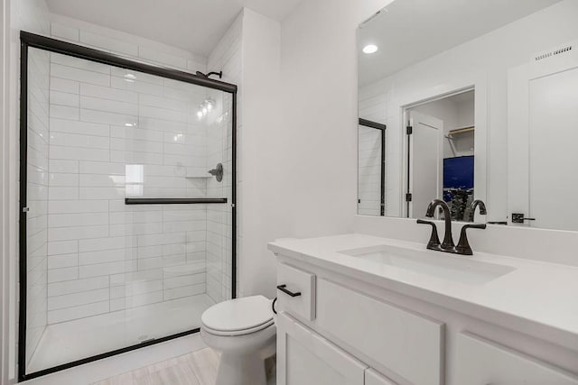 bathroom featuring a tile shower, vanity, toilet, recessed lighting, and visible vents