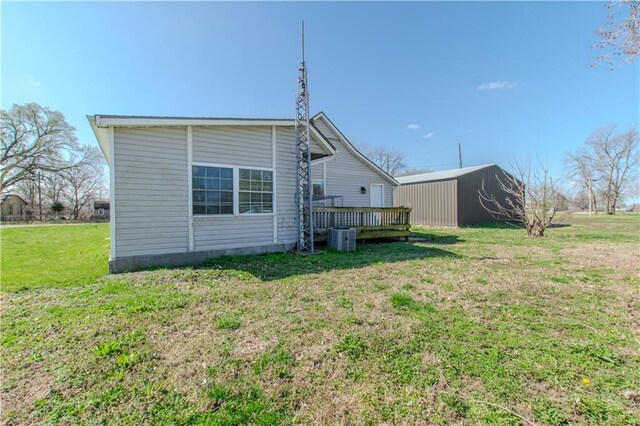 back of property with a lawn, central air condition unit, and a wooden deck