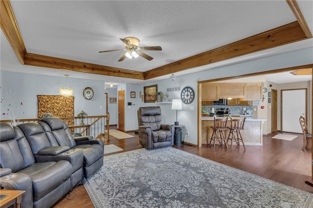 living room with a ceiling fan, a tray ceiling, baseboards, dark wood finished floors, and visible vents