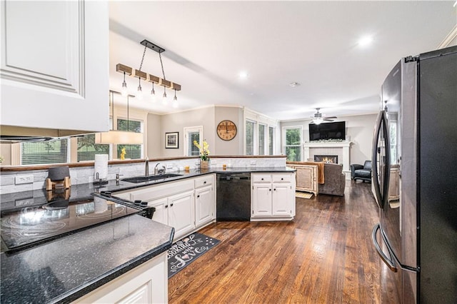 7325 Oakview St, Shawnee, KS 66216 - kitchen featuring freestanding refrigerator, black dishwasher, a ceiling fan, a warm lit fireplace, and dark wood-type flooring