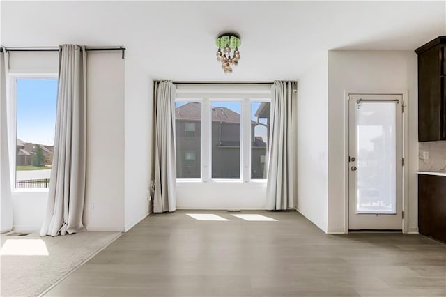 unfurnished dining area featuring light wood-style flooring, visible vents, and plenty of natural light