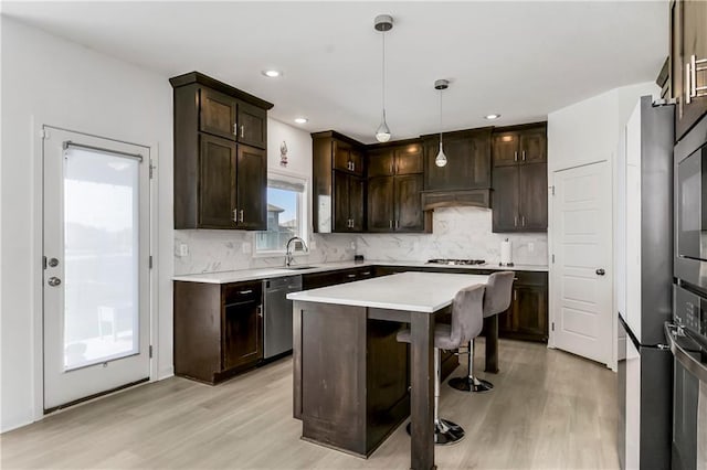 kitchen with light wood-style floors, dark brown cabinetry, stainless steel appliances, and a sink