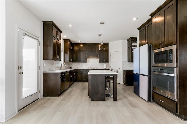 kitchen featuring light countertops, light wood-style flooring, appliances with stainless steel finishes, and dark brown cabinetry