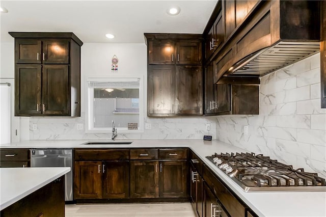 kitchen with stainless steel appliances, a sink, backsplash, light countertops, and under cabinet range hood