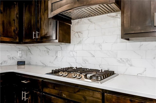 kitchen with stainless steel gas cooktop, light countertops, dark brown cabinetry, and premium range hood
