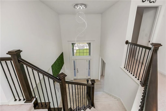 stairway with a chandelier, a towering ceiling, and baseboards