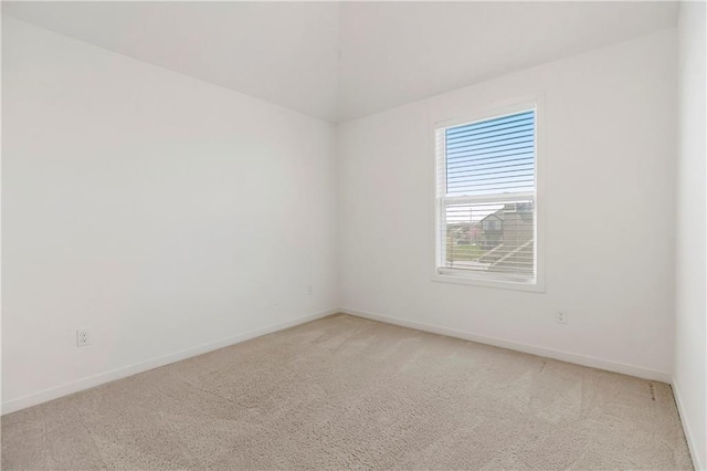 empty room featuring baseboards and light colored carpet