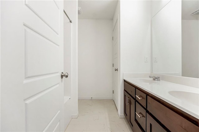 bathroom featuring marble finish floor, a sink, and double vanity