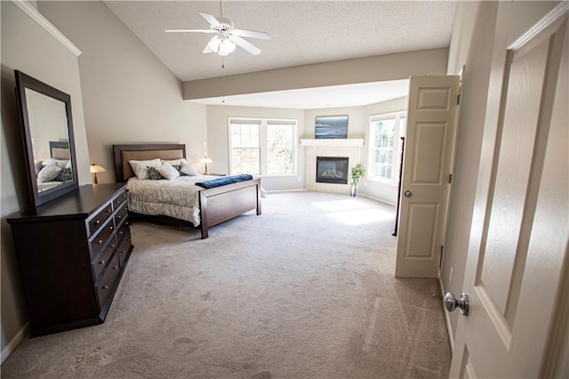 bedroom with light colored carpet, vaulted ceiling, a textured ceiling, a glass covered fireplace, and baseboards