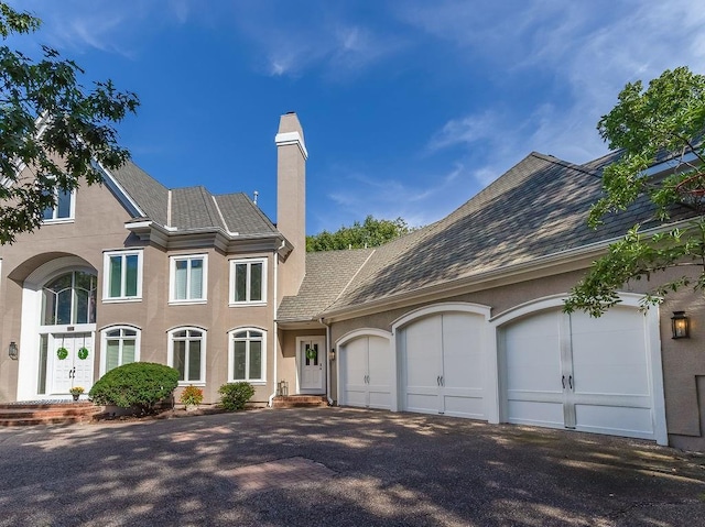 329 Mojave Street W, St, Lake Quivira, KS 66217 - view of front of home with stucco siding, a chimney, a garage, and asphalt driveway