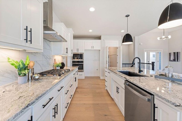 kitchen featuring stainless steel appliances, a sink, wall chimney range hood, white cabinetry, and recessed lighting