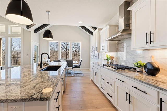 kitchen featuring a sink, wall chimney exhaust hood, stainless steel gas cooktop, healthy amount of natural light, and recessed lighting