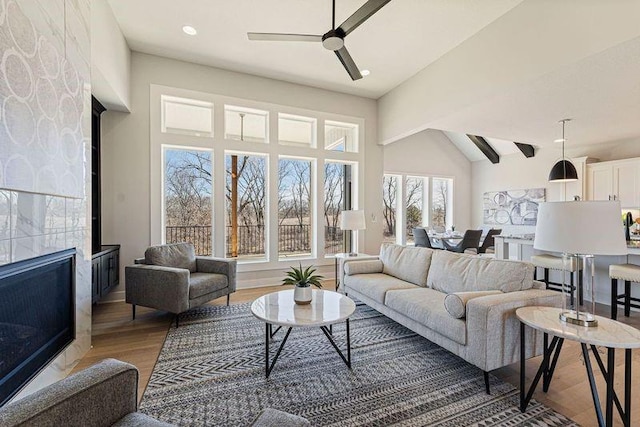 living room with ceiling fan, light wood-type flooring, and vaulted ceiling