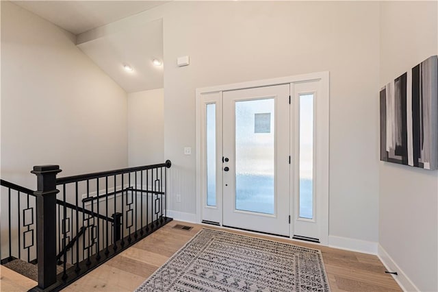 entrance foyer with wood finished floors, baseboards, and vaulted ceiling