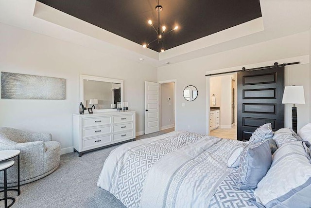 bedroom featuring a barn door, a raised ceiling, baseboards, light carpet, and ensuite bathroom