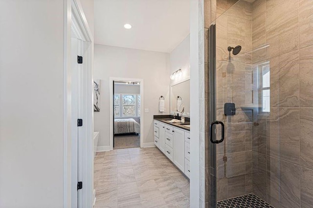 ensuite bathroom featuring a shower stall, vanity, and baseboards