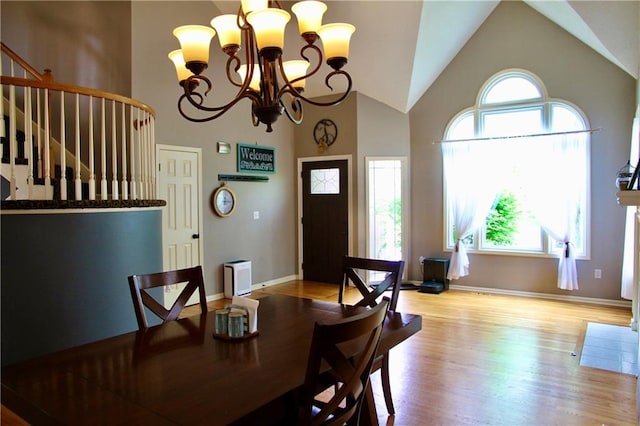 dining room with stairs, baseboards, high vaulted ceiling, light wood-type flooring, and a chandelier