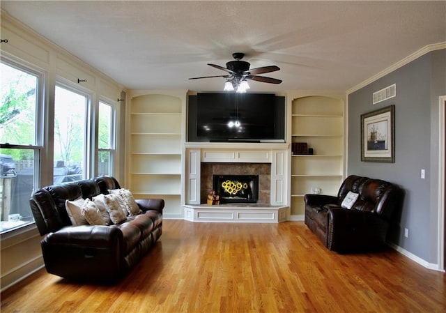 living area featuring visible vents, a ceiling fan, built in features, and light wood-type flooring