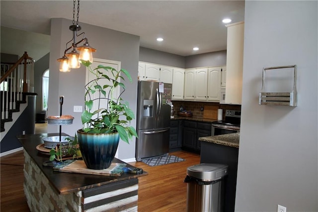 kitchen with stainless steel appliances, white cabinetry, wood finished floors, backsplash, and pendant lighting