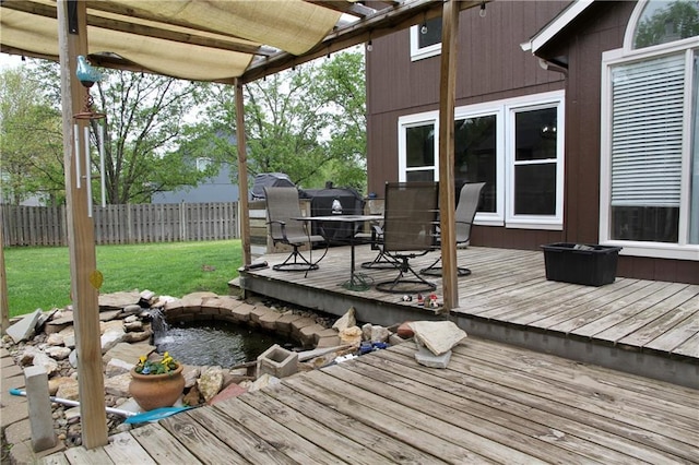 deck featuring a yard, a small pond, outdoor dining area, and a fenced backyard