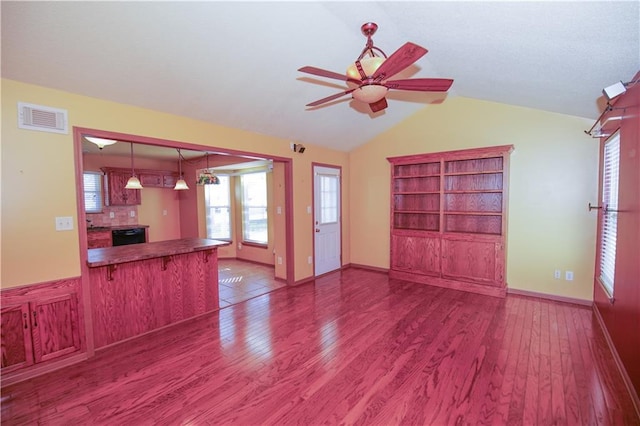 unfurnished living room with ceiling fan, vaulted ceiling, visible vents, wood finished floors, and baseboards