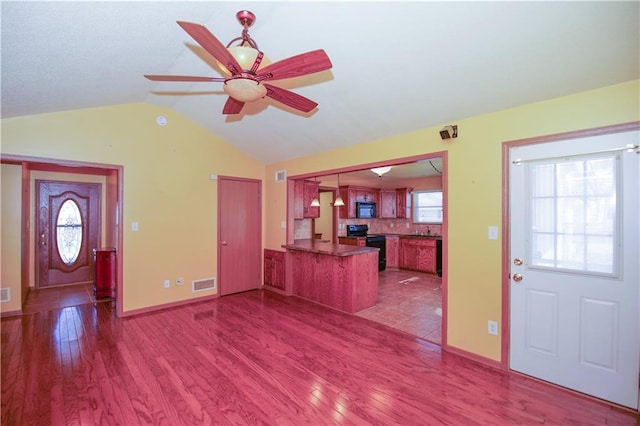 foyer featuring visible vents, ceiling fan, vaulted ceiling, and wood finished floors