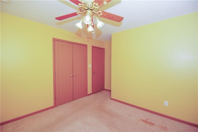 unfurnished bedroom with baseboards, ceiling fan, two closets, and light carpet