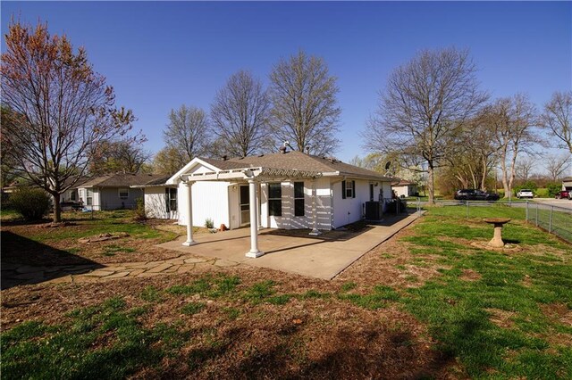 rear view of house with central air condition unit, a yard, stucco siding, a patio, and fence