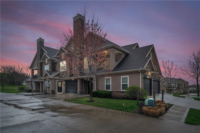 view of front of house featuring driveway, a chimney, stone siding, stucco siding, and a lawn